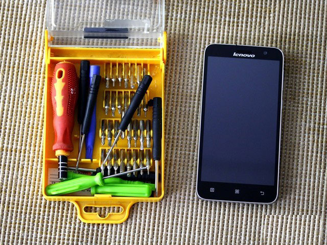 拆机前的准备工作，依然是手机事业部常用的拆机工具箱。其中包含多种不同类型的改锥头，撬棒，以及几个常用的螺丝刀，还有更利于进行细节工作的镊子。当然右边即为等待被拆卸并查看内在的联想手机A8，整体看去相当的简洁大方。