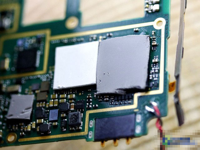 好吧看过了主板正面之后，让我们翻过来看看主板的背后（下方）都有些什么。这是刚刚把主板翻过来的样子，图中的几个灰色白色是啥玩意？DIY用户应该一看就知道它们正是硅脂，用于覆盖在CPU等硬件上方，主要目的是更好的散热。